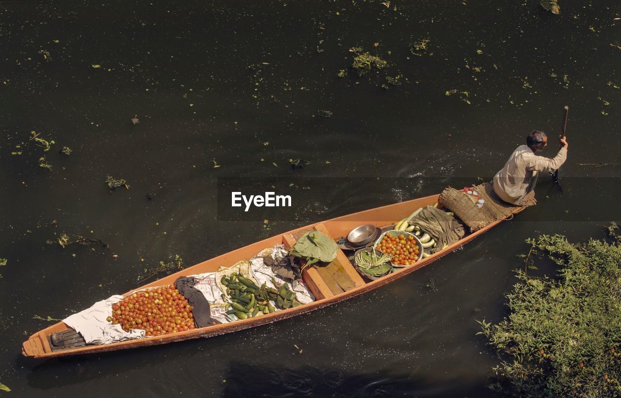 High angle view of man with vegetables in boat rowing on lake