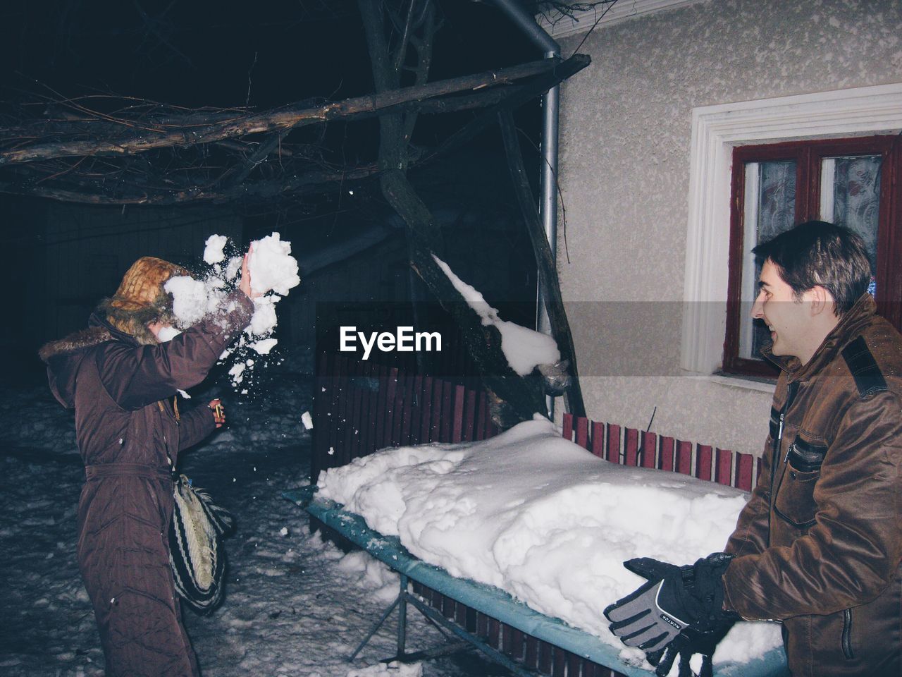 Siblings playing with snow at night