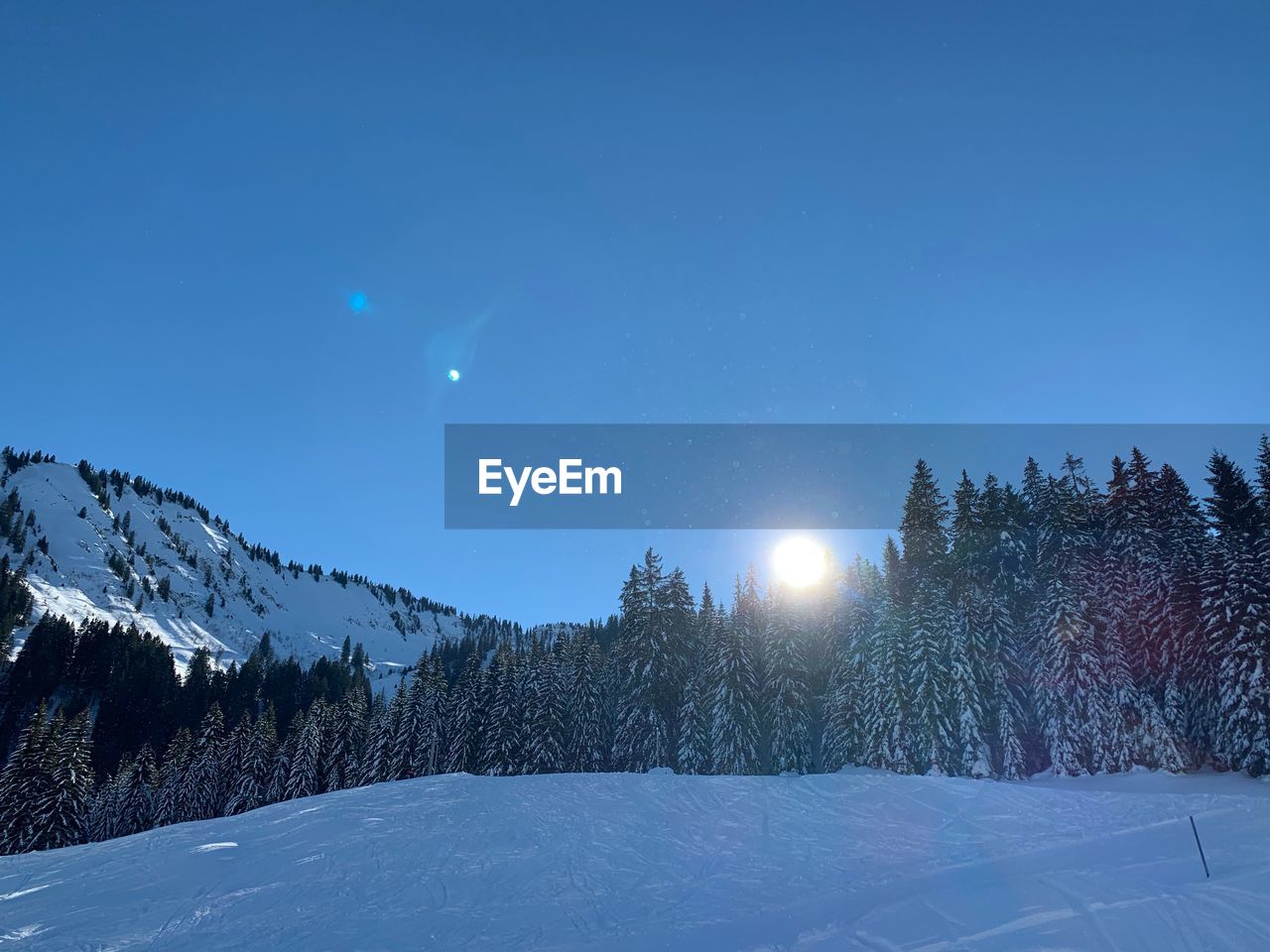 Scenic view of snow covered landscape against blue sky