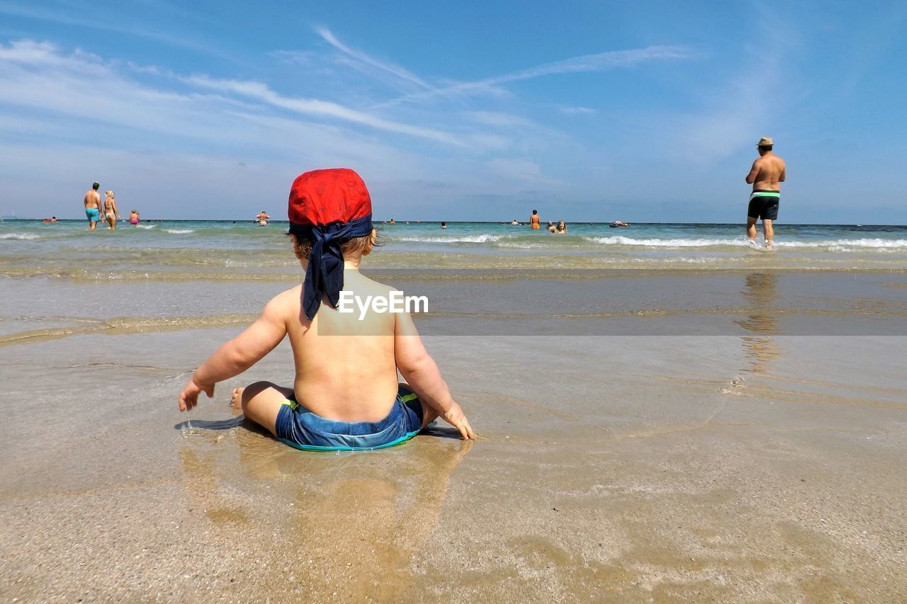 Rear view of baby sitting on beach