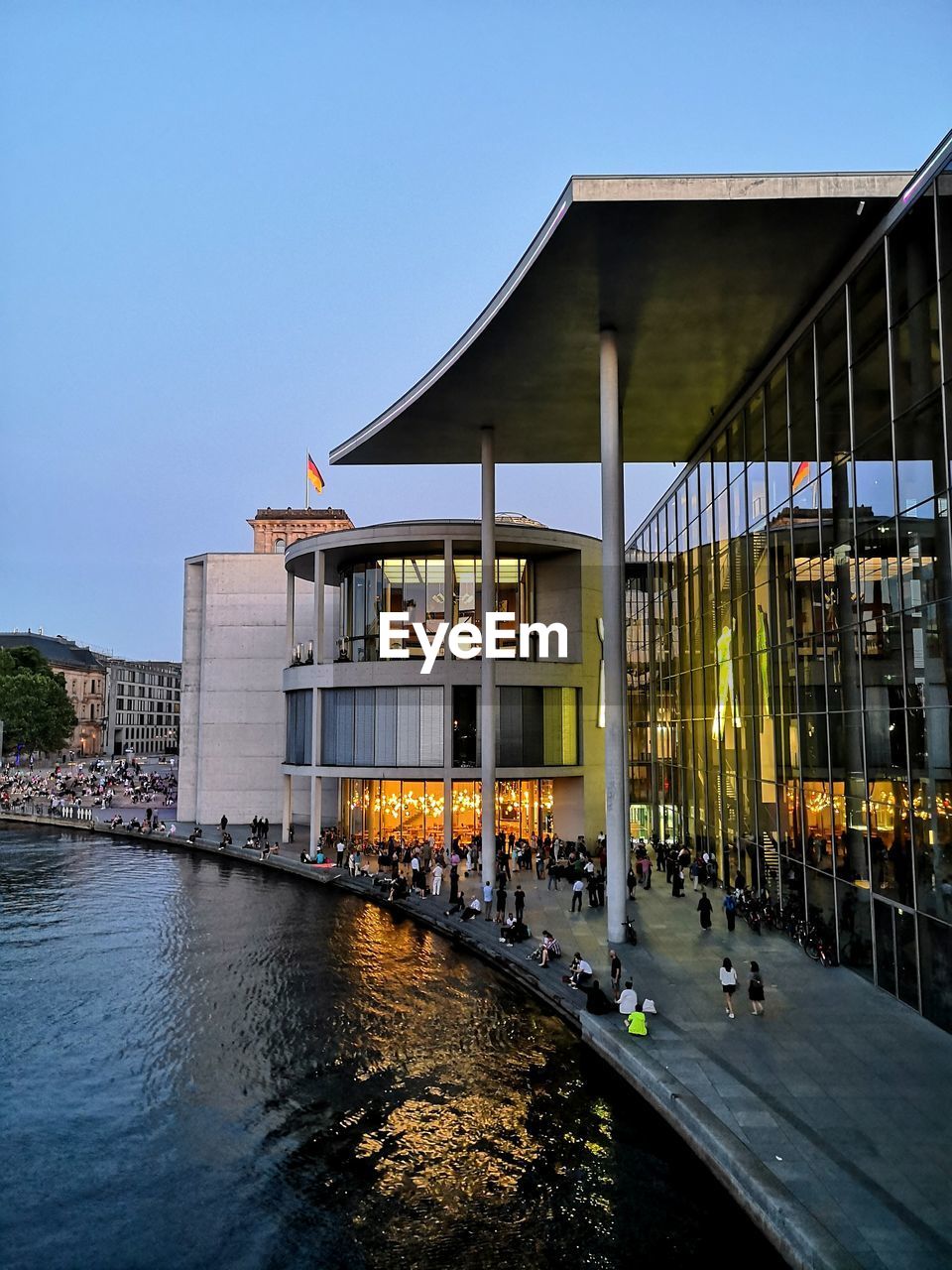 Modern building on a river side with water reflection during sunset