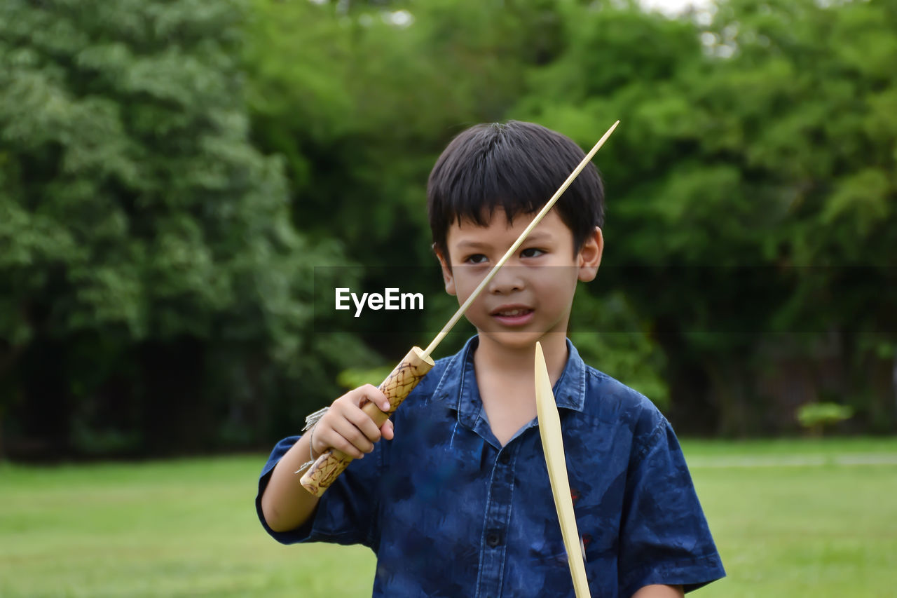 Boy holding wooden equipment while standing outdoors