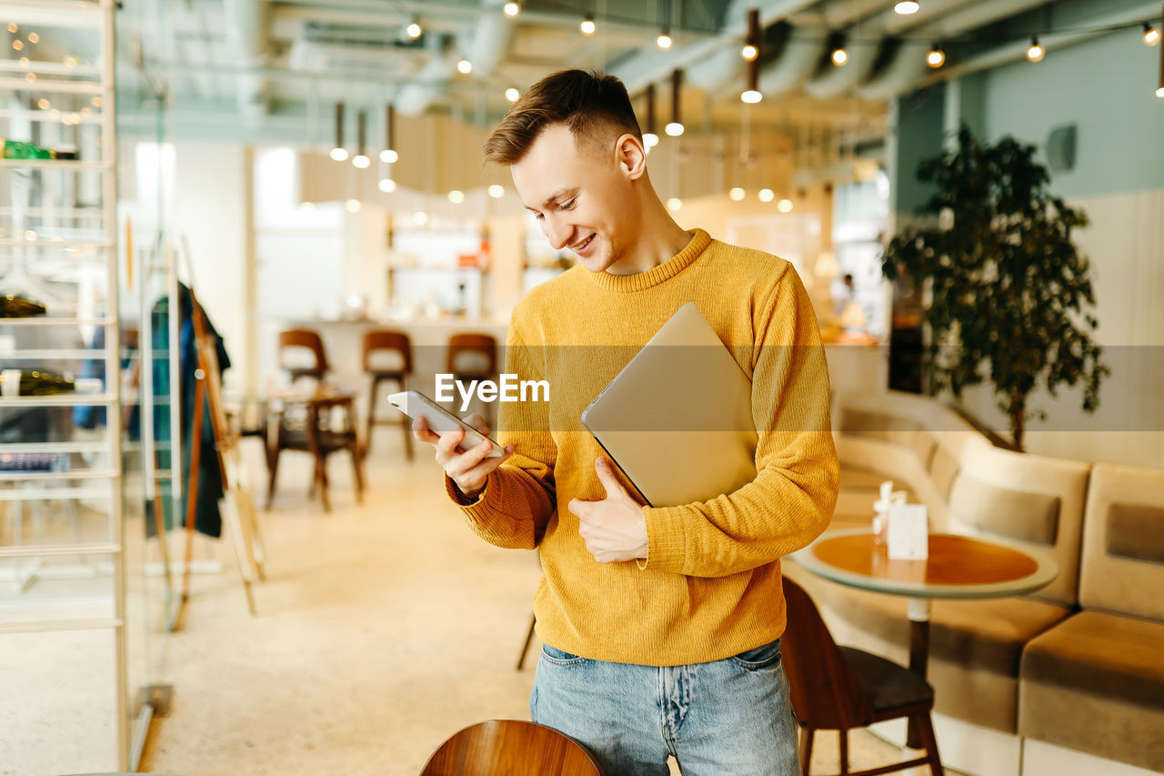 A young man freelance businessman uses wireless technology while working while sitting in a cafe