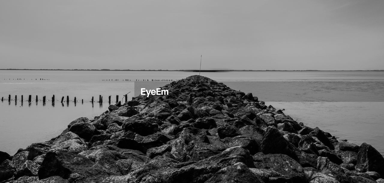 ROCK FORMATIONS ON SHORE AGAINST SKY