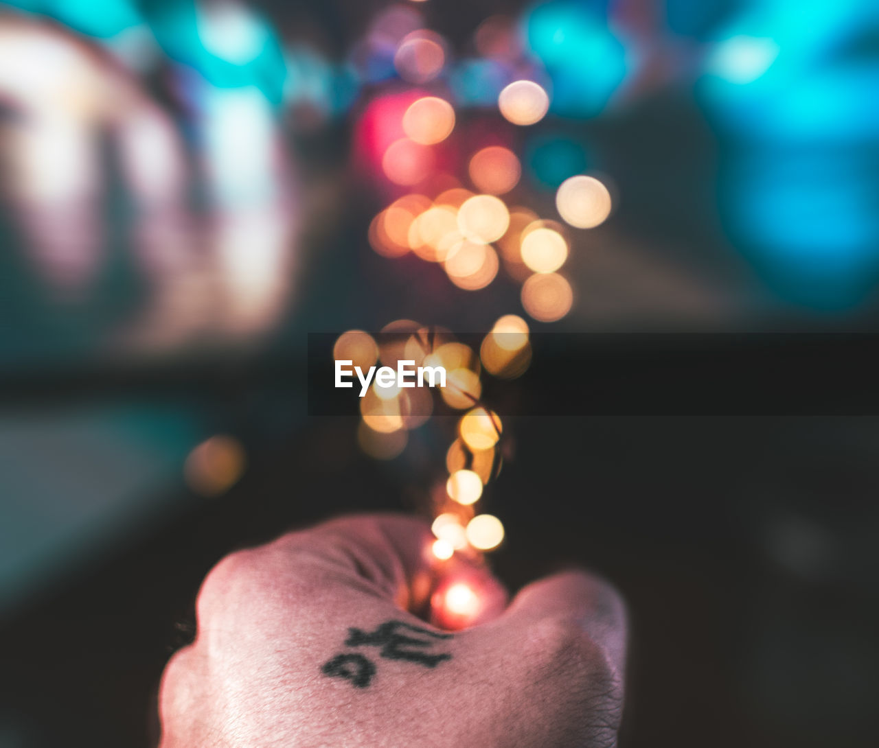 Cropped hand of man holding illuminated lighting equipment at night