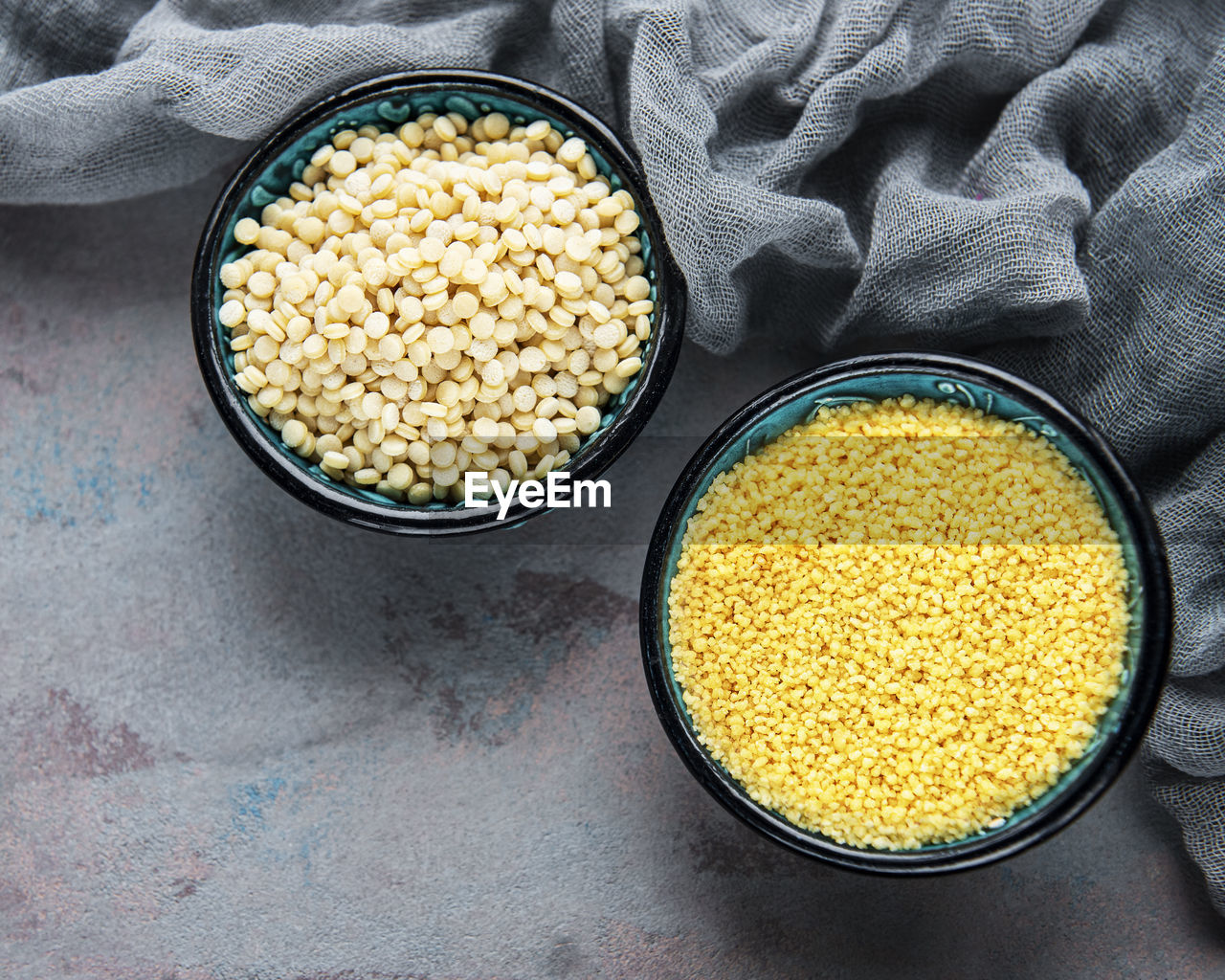 Raw couscous in a bowls on the grey concrete background