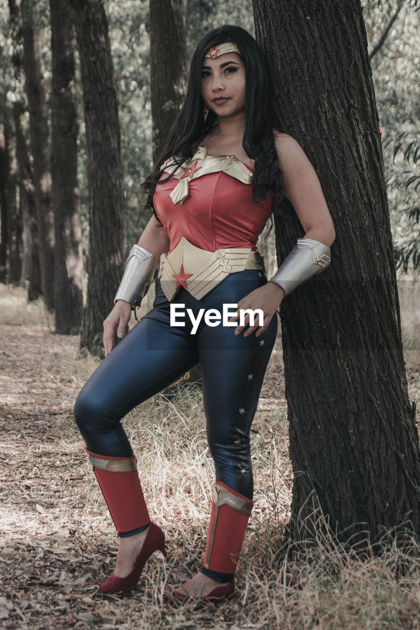 FULL LENGTH PORTRAIT OF WOMAN ON TREE TRUNK