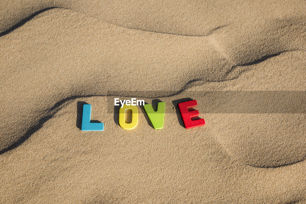 Love written out with colourful wooden letters text on sand of a dune