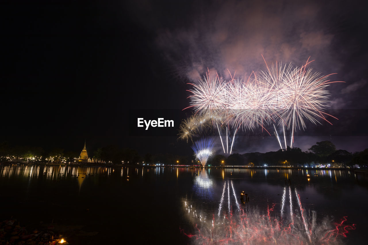 FIREWORK DISPLAY OVER RIVER AGAINST SKY