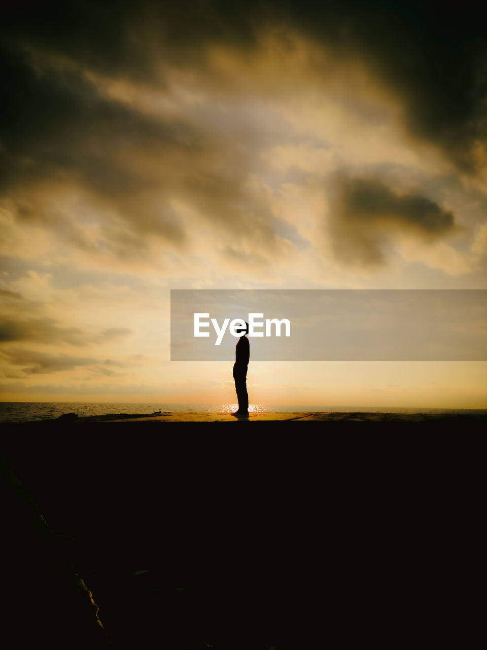 Silhouette man standing on beach against sky during sunset