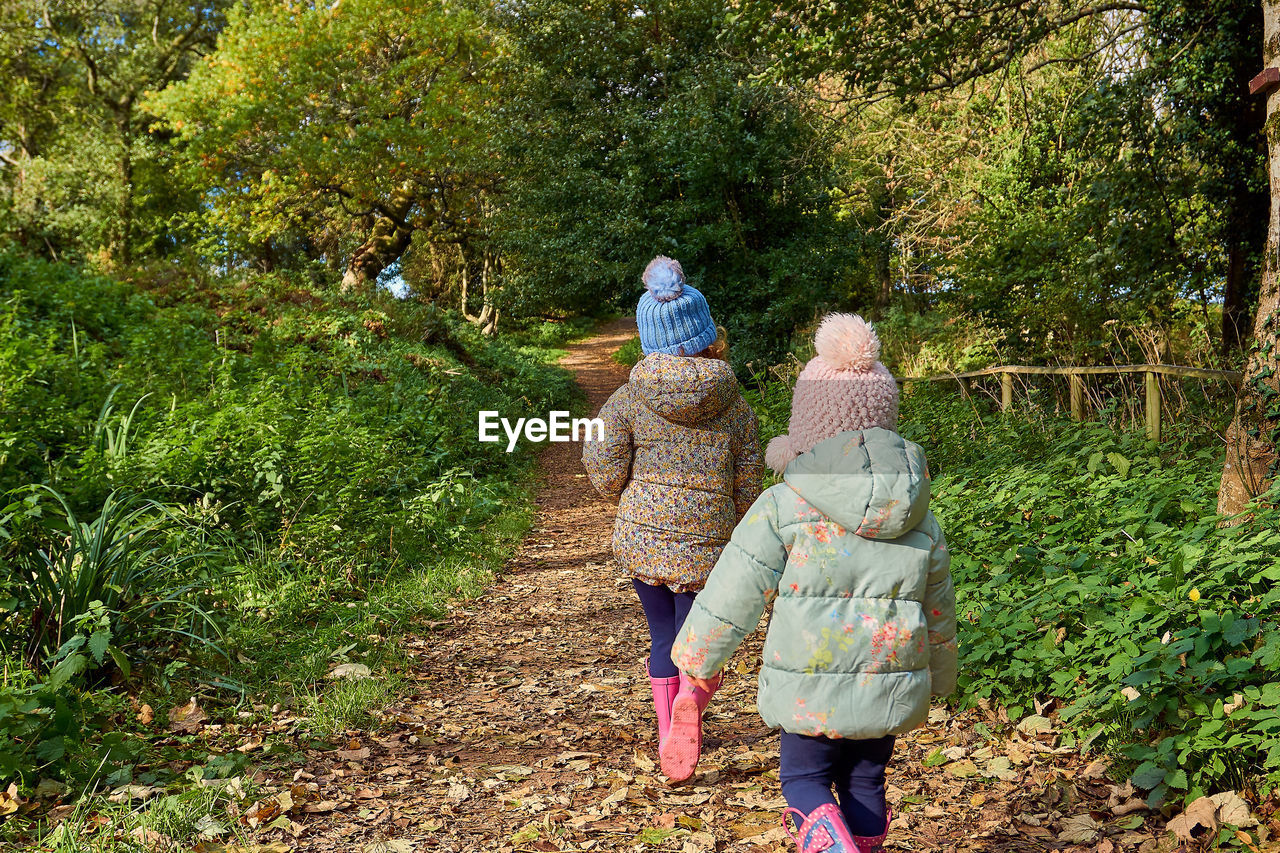 Sisters walking against trees during winter