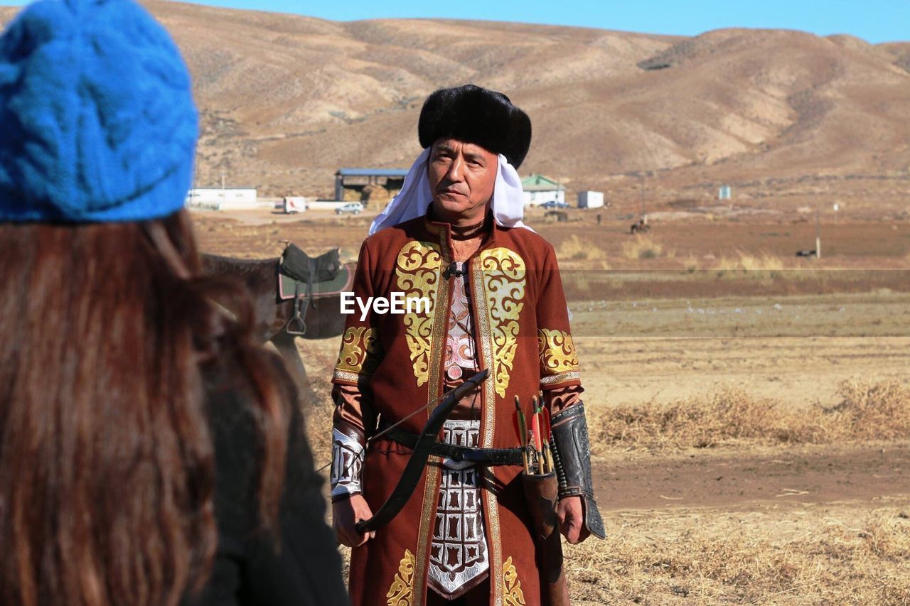 Rear view of woman looking at man wearing traditional clothes