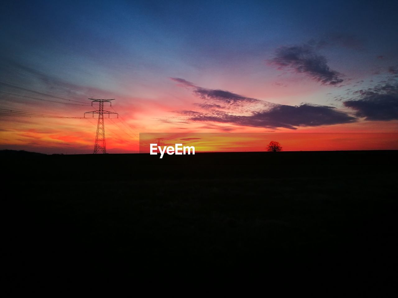 SILHOUETTE OF ELECTRICITY PYLON AGAINST SKY AT SUNSET