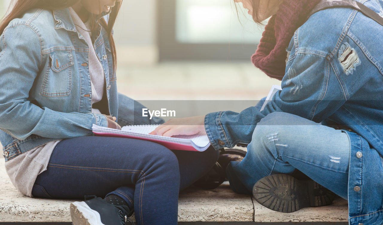 Two young women study on a bench.