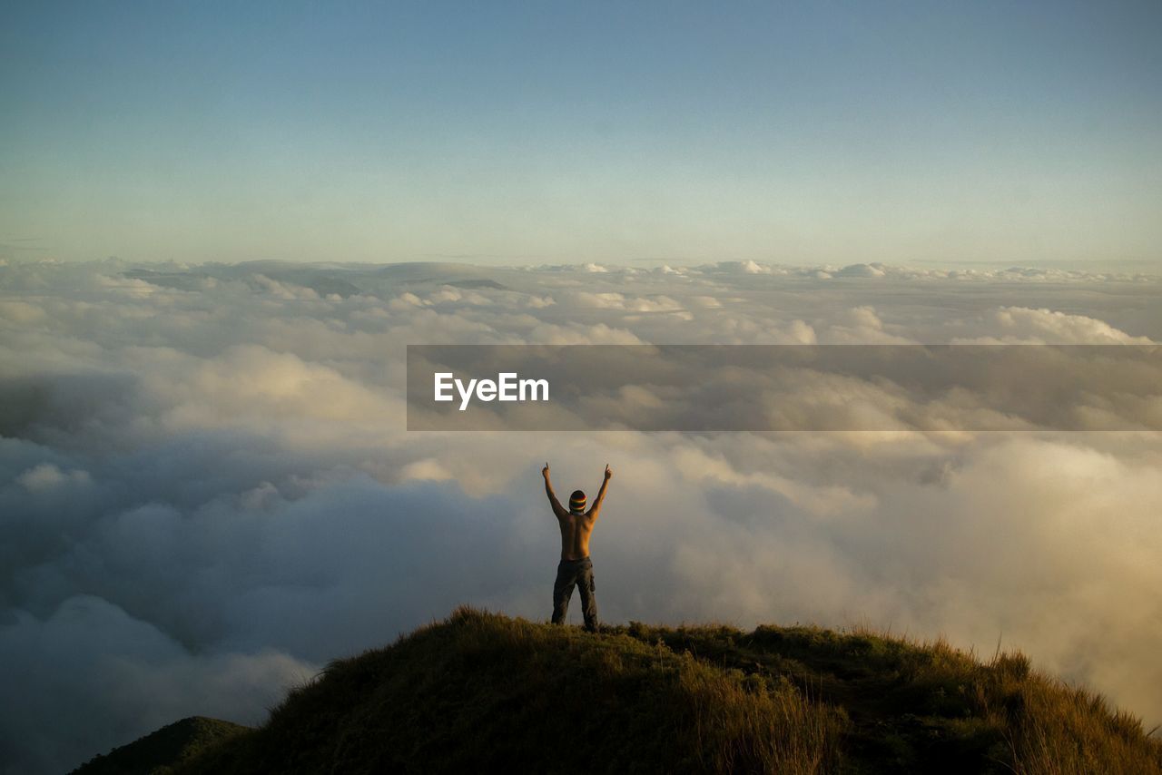 Rear view of man on mountain peak against sky
