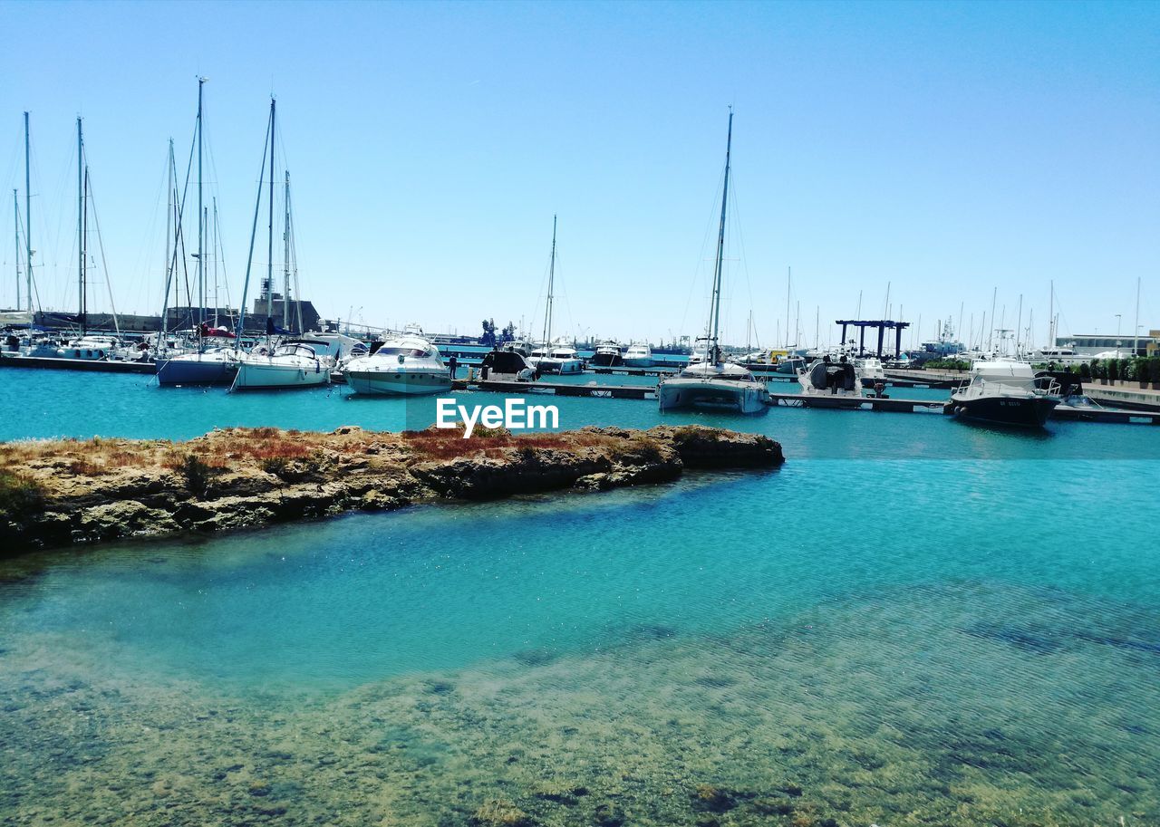 SAILBOATS MOORED IN HARBOR