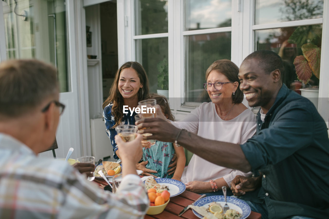 Happy multi-generation family toasting drinks at table during garden party