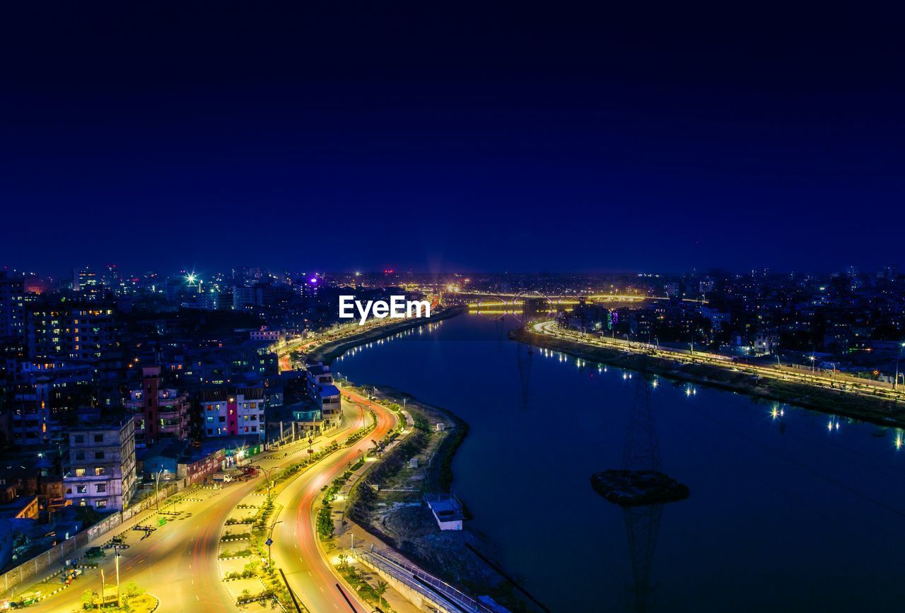 Illuminated cityscape view with river at night