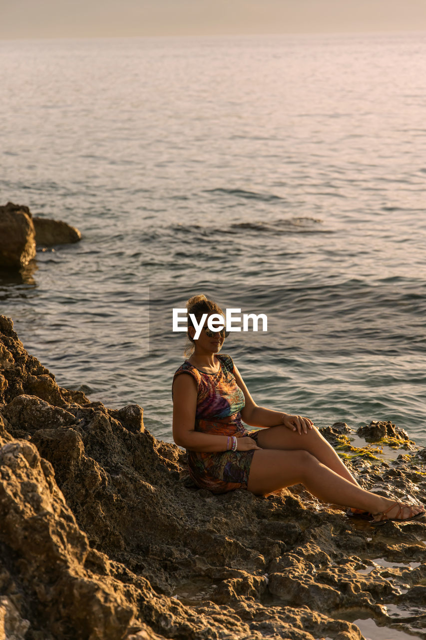 Young woman sitting on rock at beach