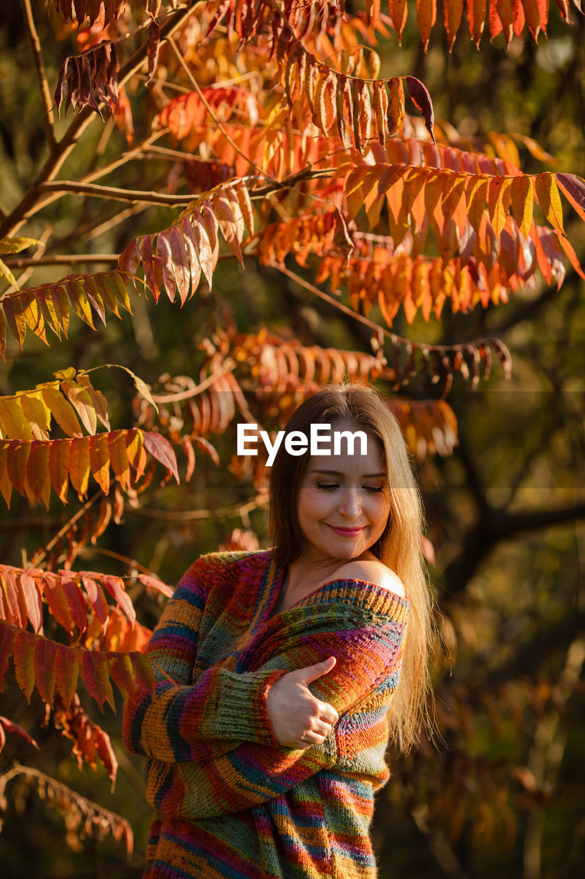 portrait of smiling young woman standing against plants