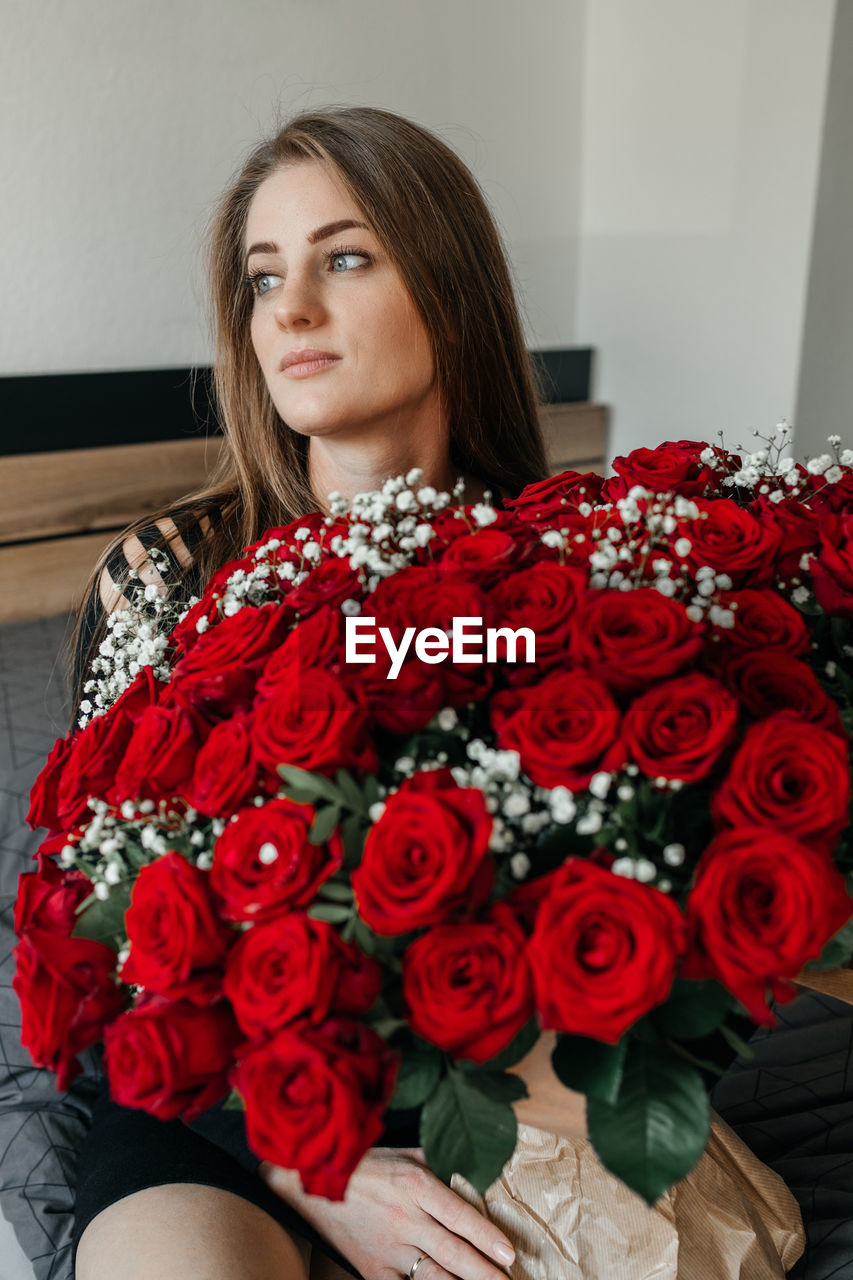 Charming young woman with a huge bouquet of red roses. flower delivery for holidays and memorable