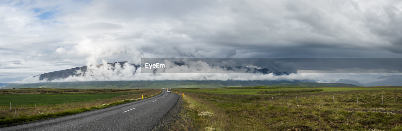 Road amidst field against sky