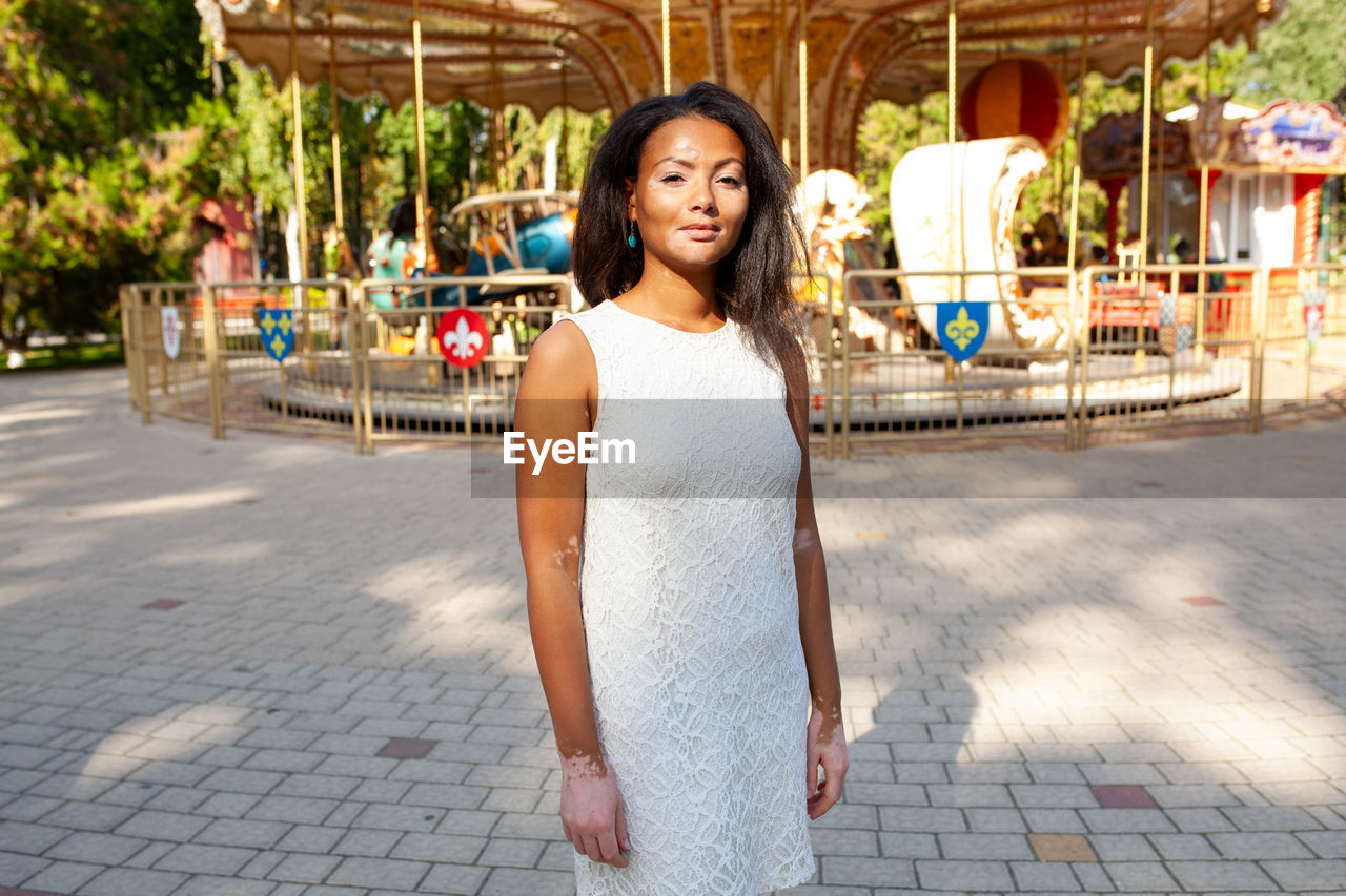 portrait of young woman standing on footpath