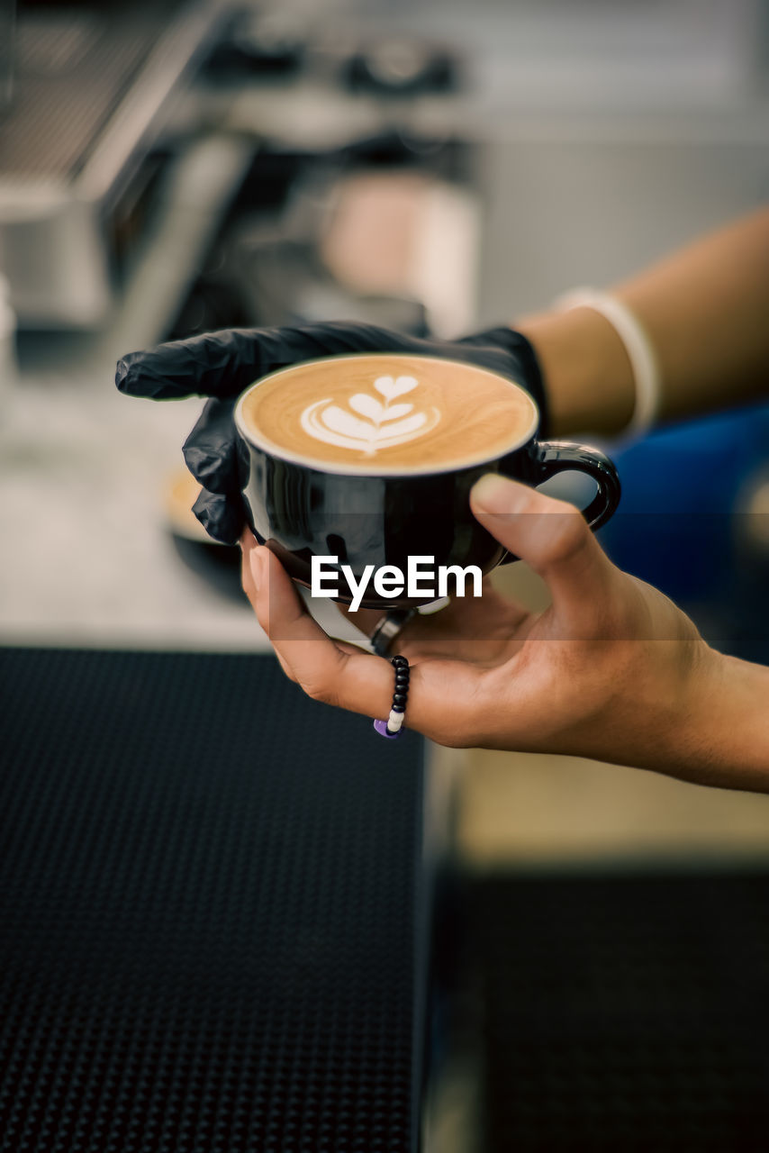 Cropped hand holding coffee at table