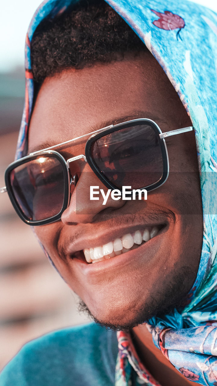 Close-up portrait of a smiling young man wearing sunglasses