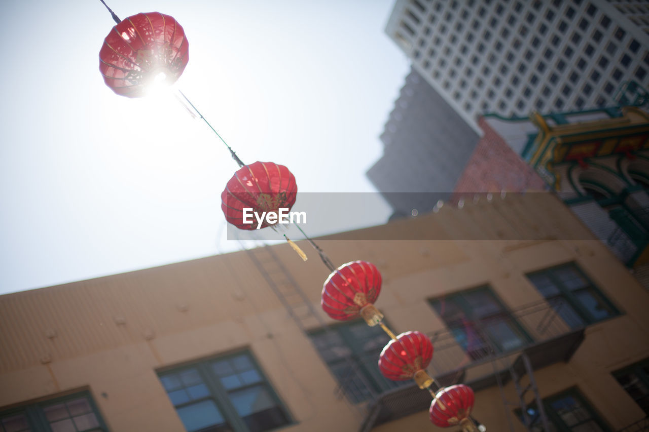 Low angle view of chinese lanterns hanging against buildings on sunny day