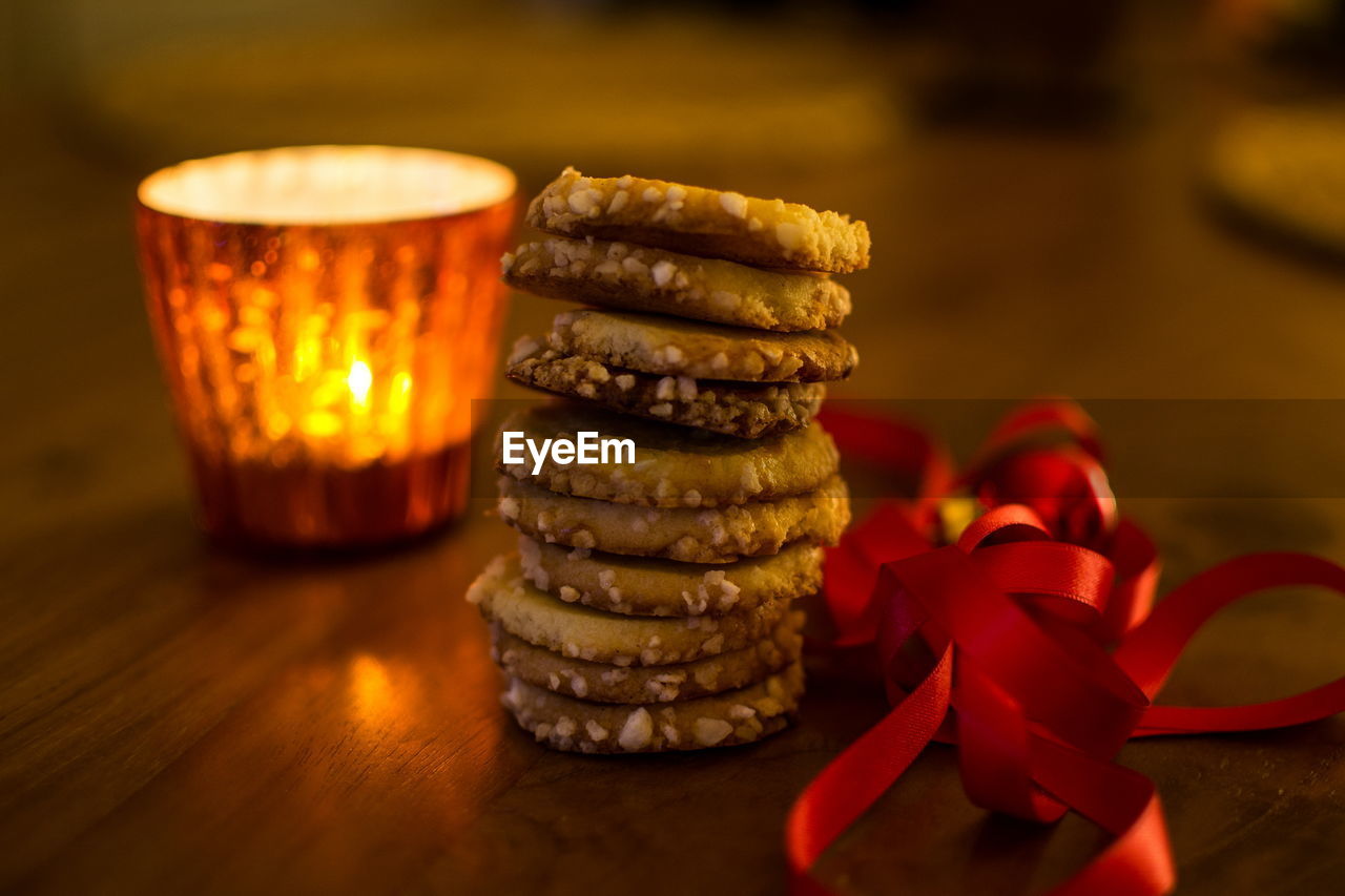 Stack of cookies by red ribbon and lit lamp