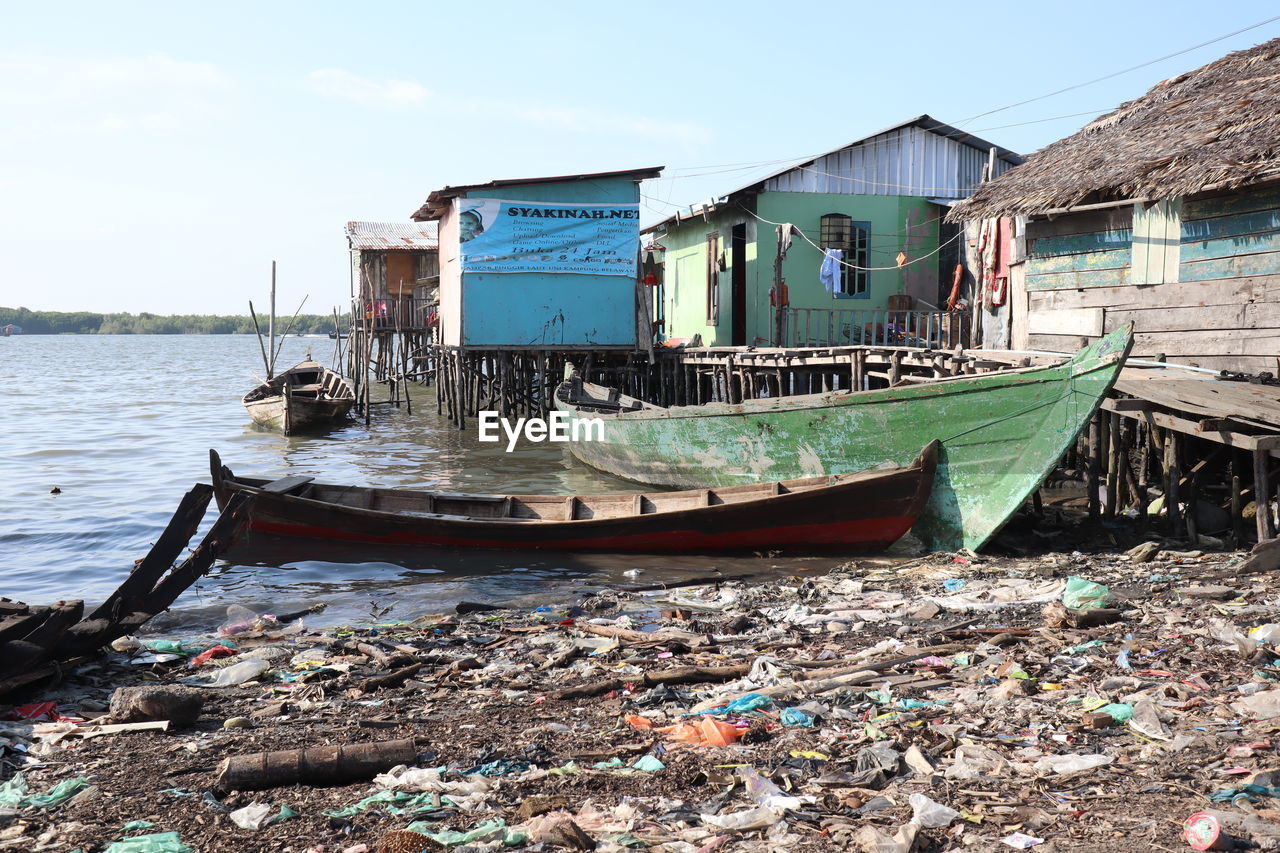 BOATS MOORED ON SHORE AGAINST SKY