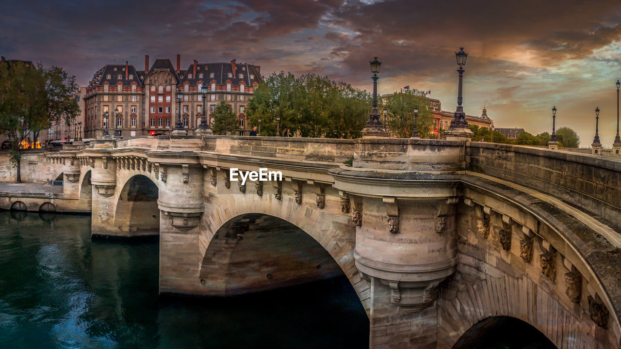 Arch bridge over river against cloudy sky