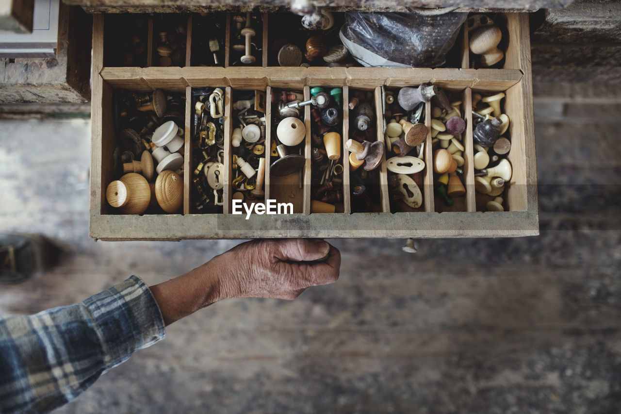 Cropped image of craftsperson opening drawer with knobs at workshop