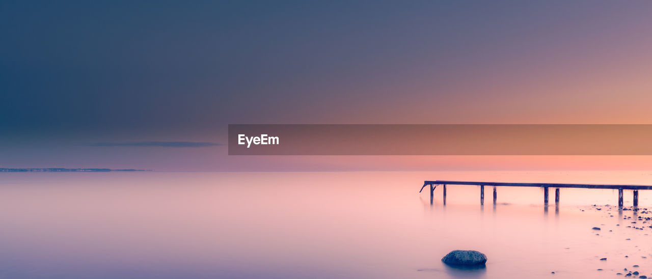 silhouette pier over sea against sky during sunset