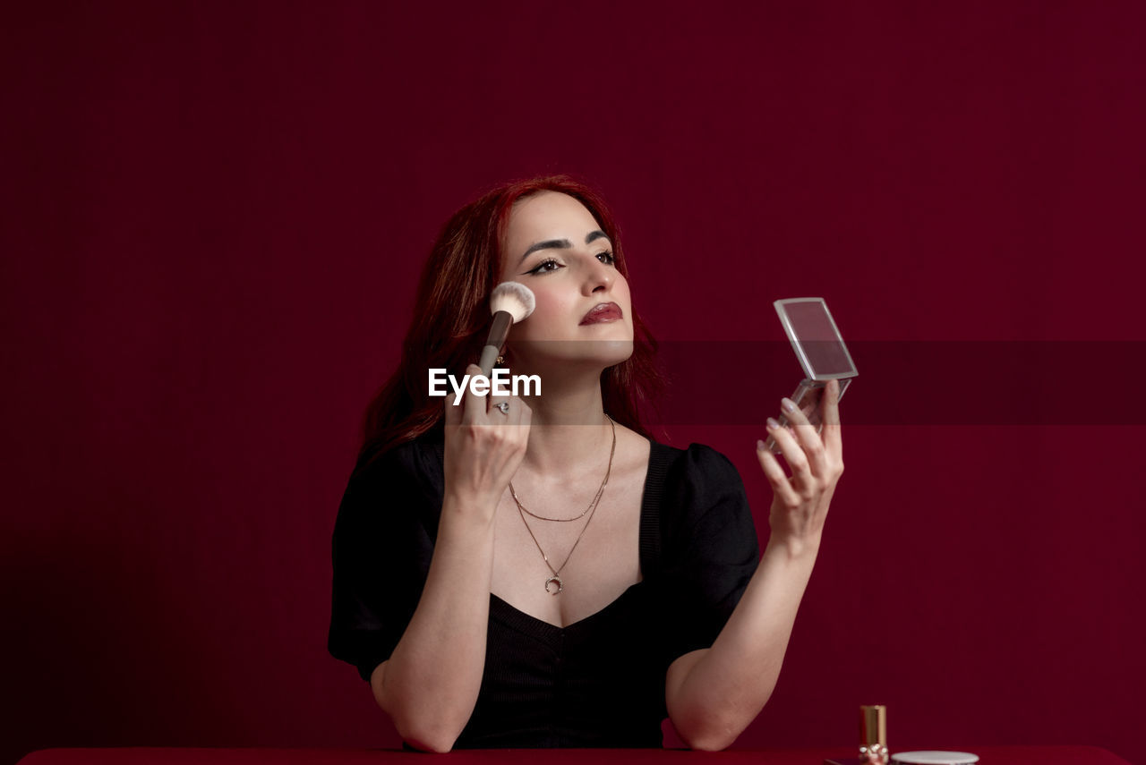 Woman holding makeup brushes against an isolated background.