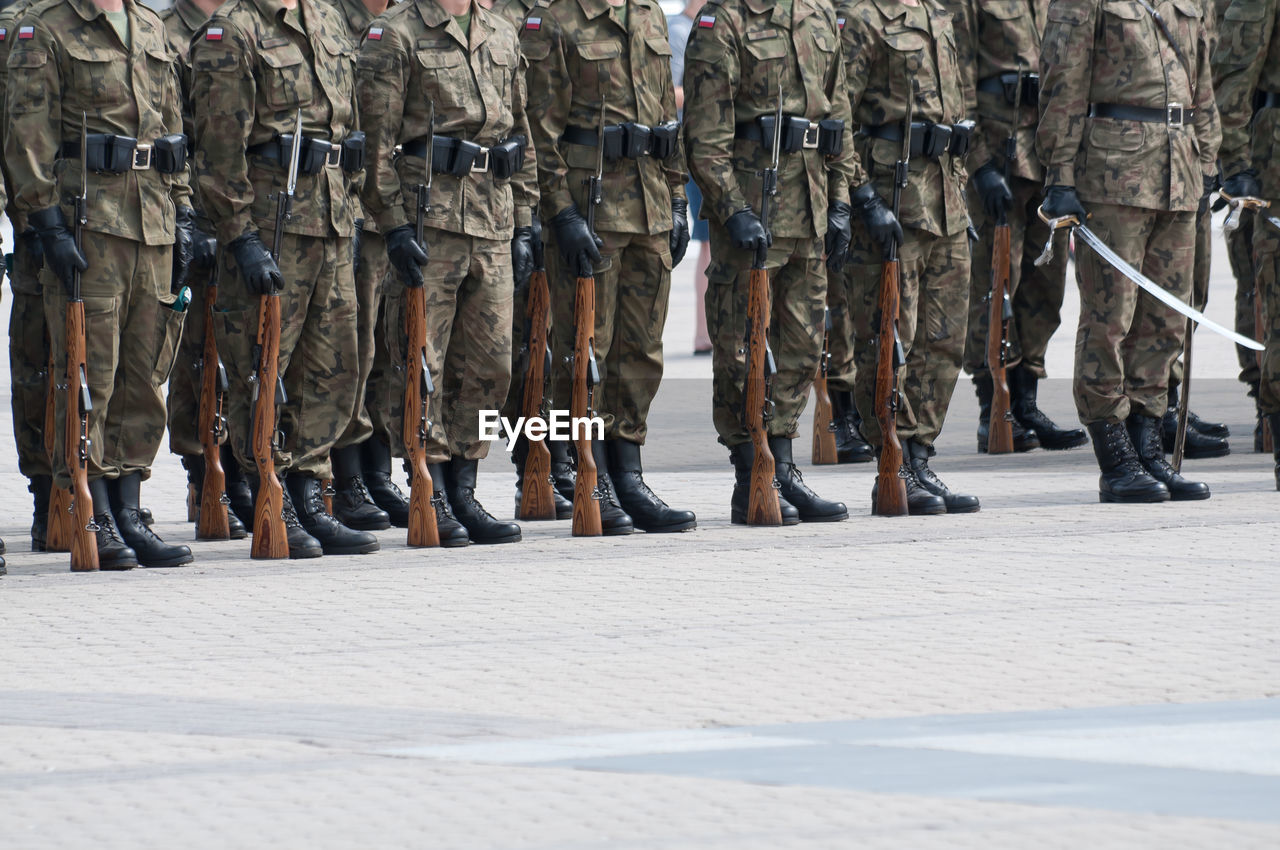 Low section of soldiers standing on footpath in city