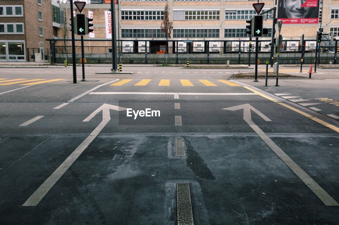 Arrow signs on road against buildings in city