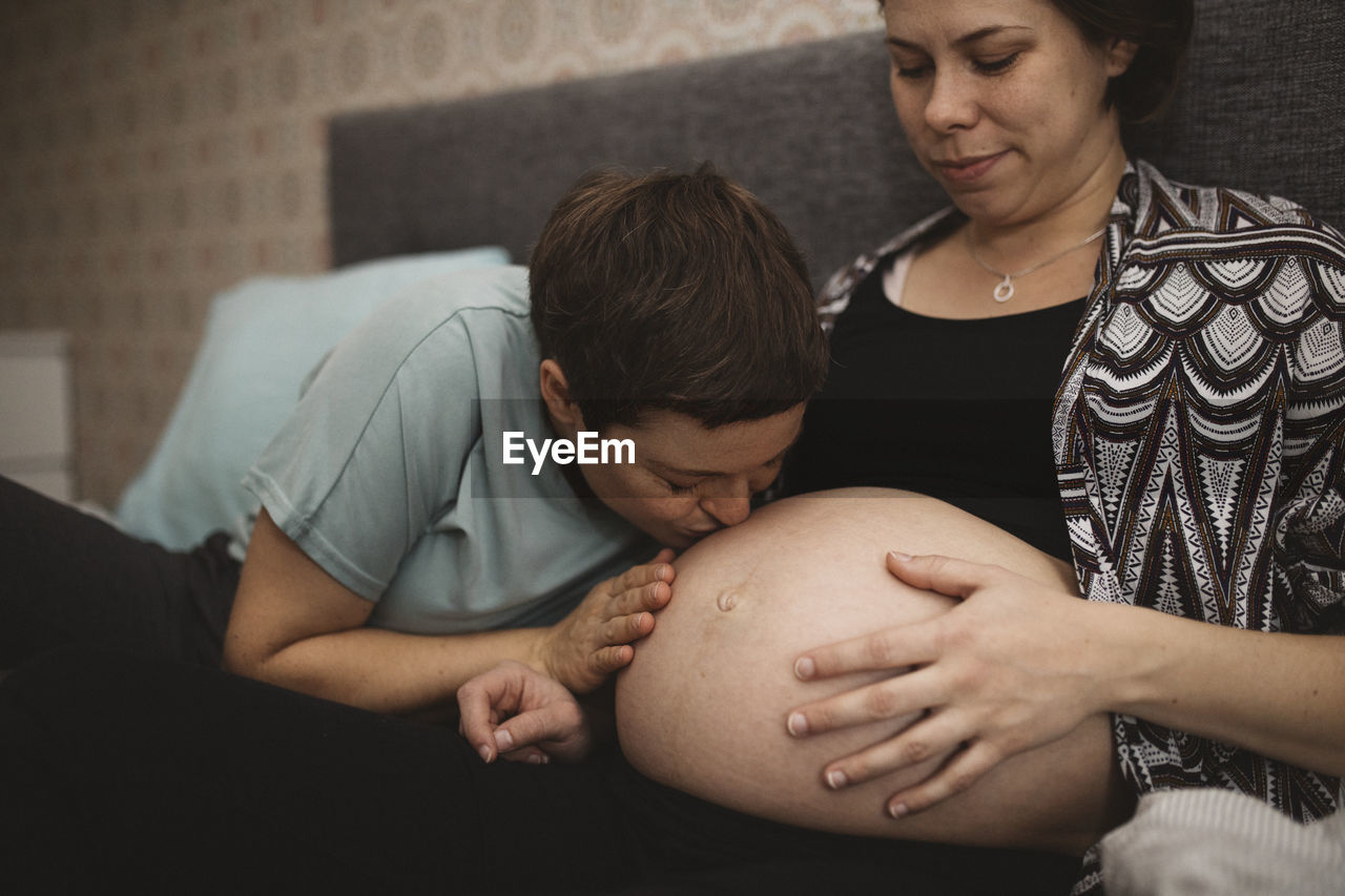 Woman kissing pregnant girlfriend's belly