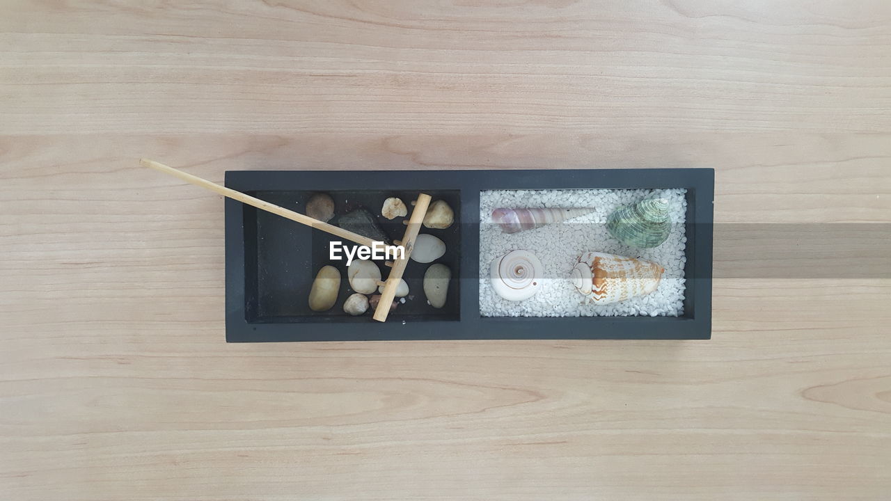 Directly above shot of seashells and pebbles in container on table