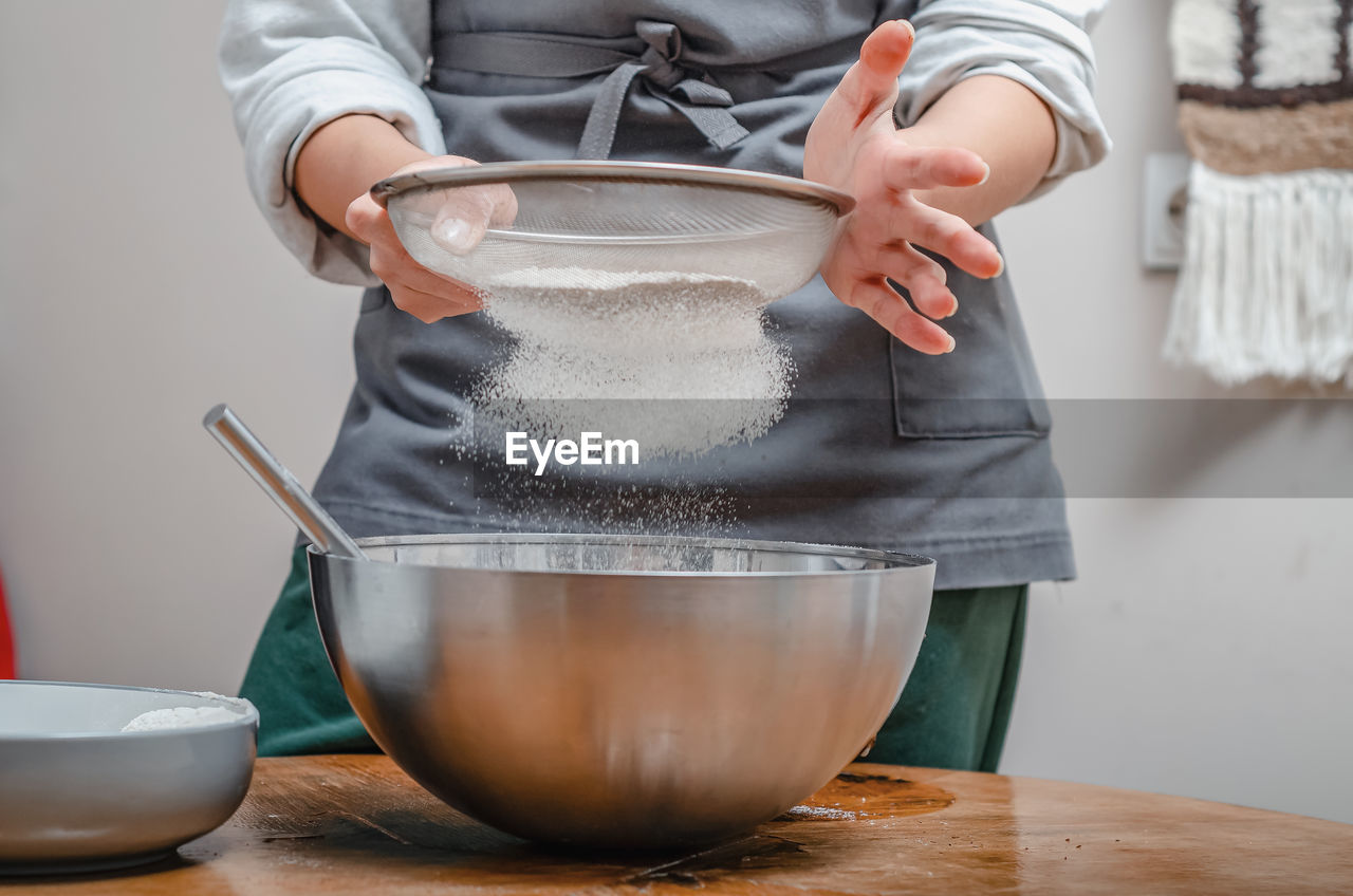 Cook sifts flour through a sieve to make dough