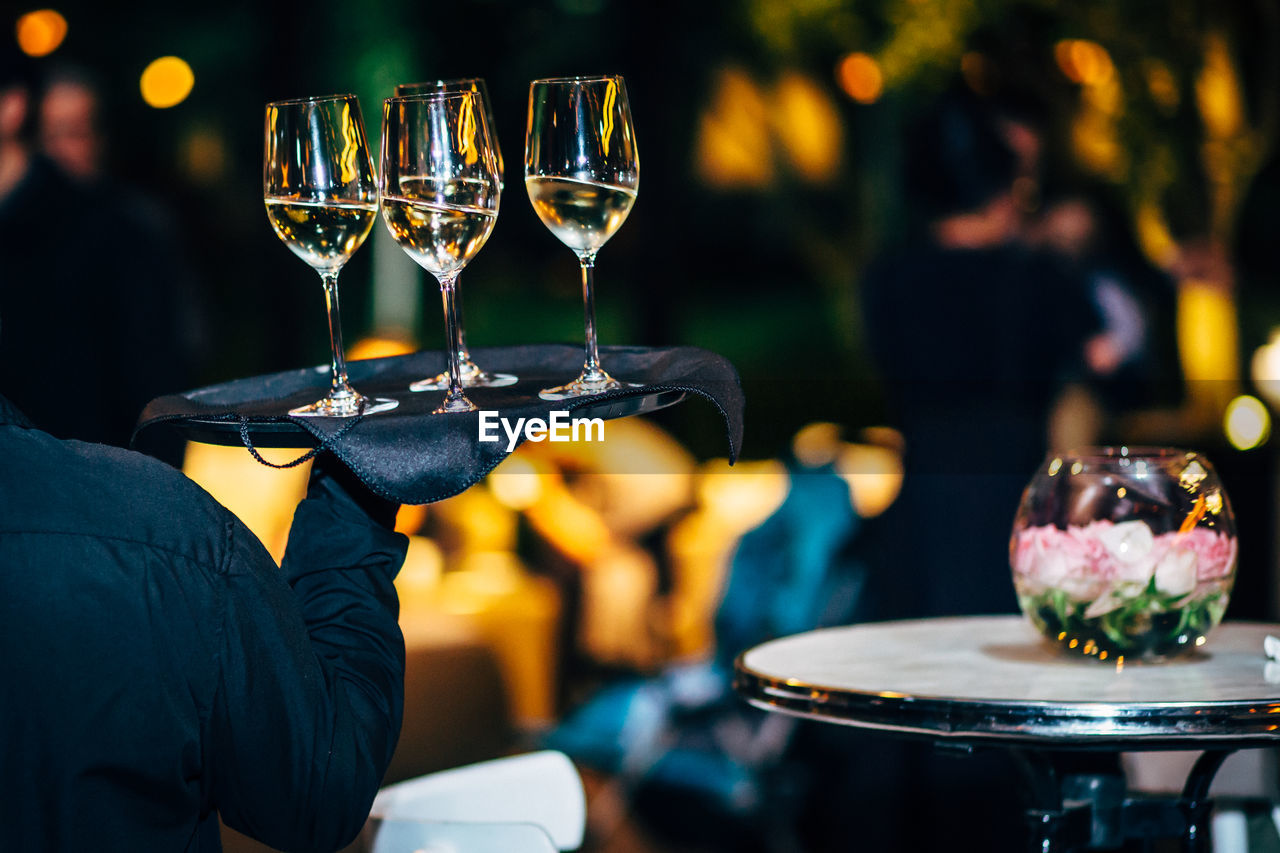 Rear view of waiter carrying champagne at restaurant