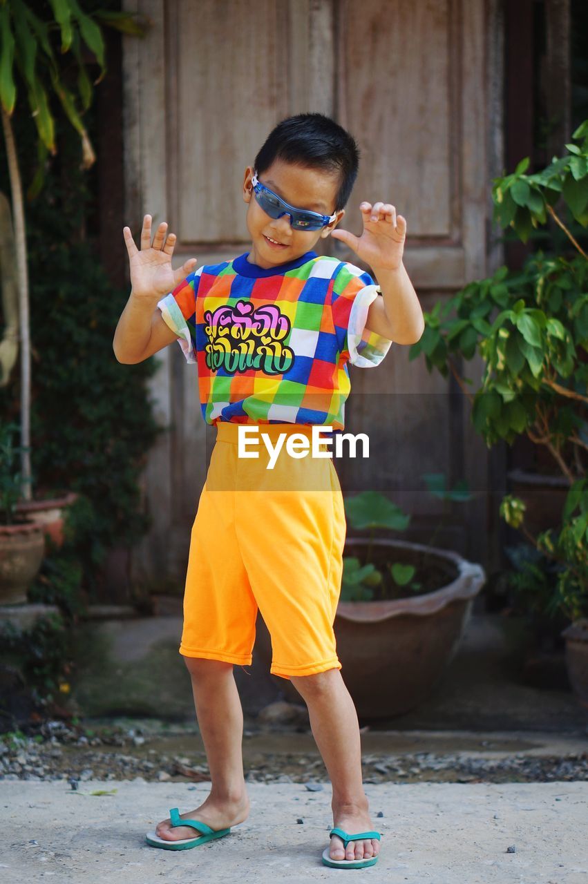 Full length of boy standing with arms raised