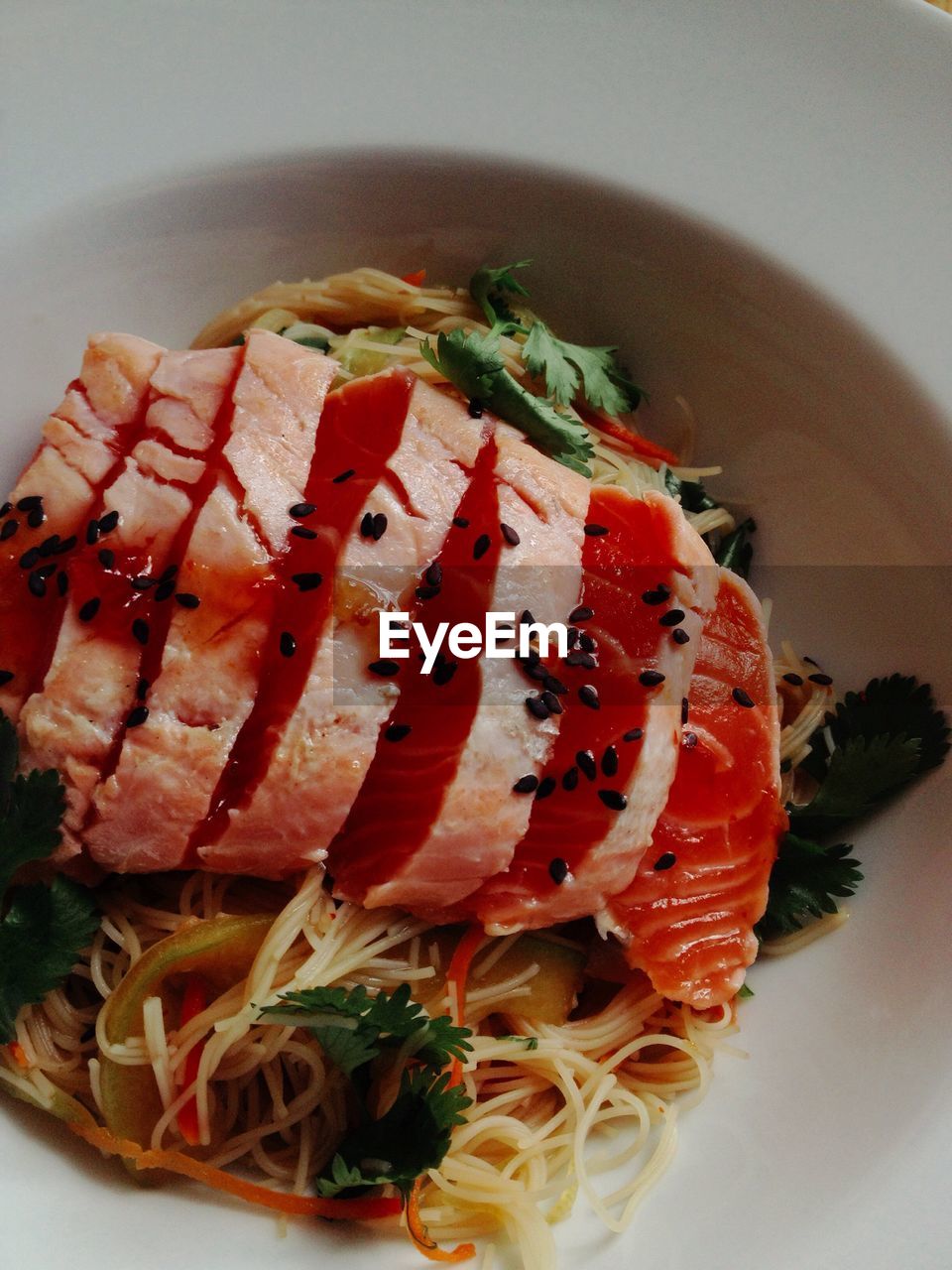 Close-up of salmon slices on noodles in plate