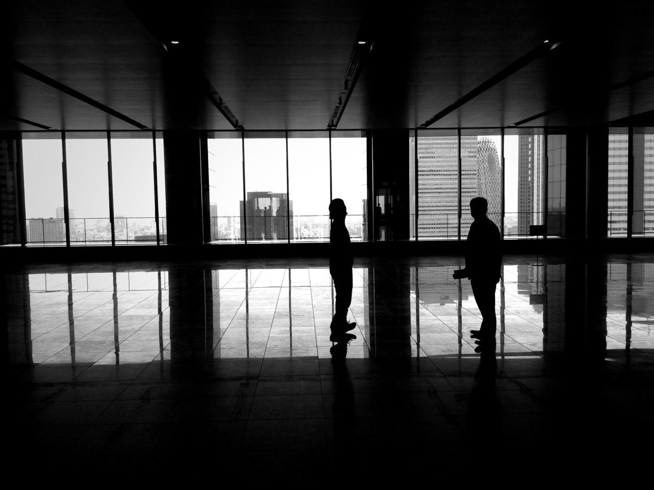 Two silhouette people standing in office