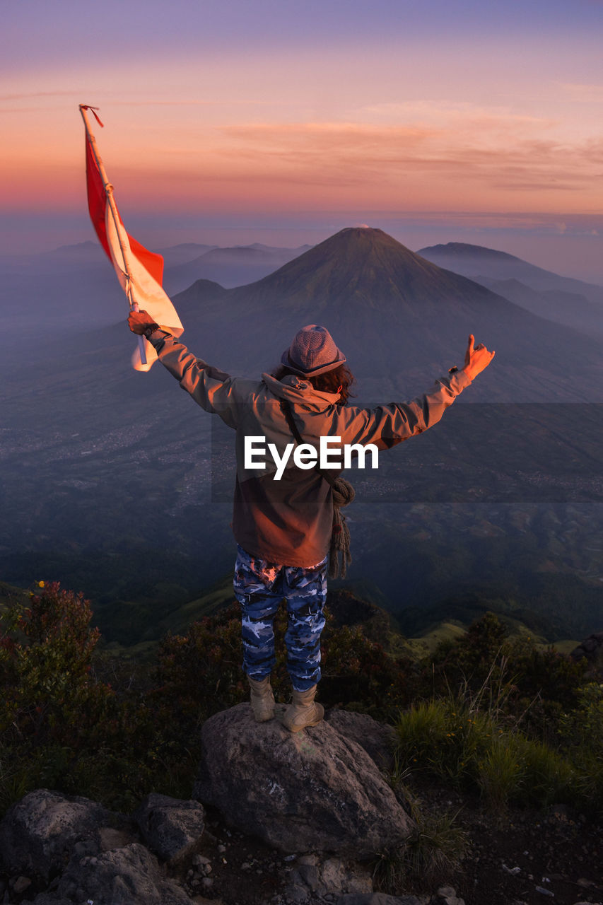 Rear view of person standing on rock against sky