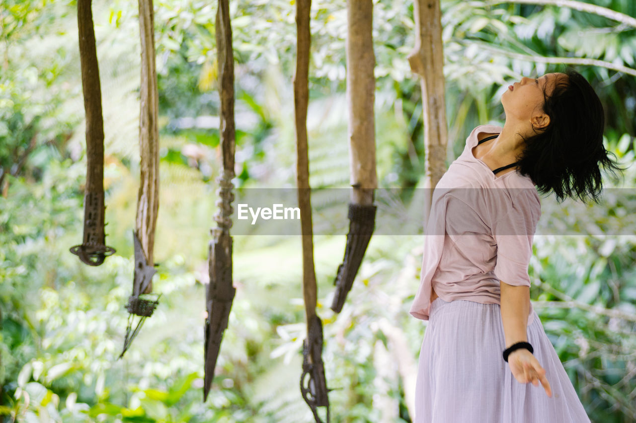 WOMAN STANDING ON TREE TRUNK IN FOREST