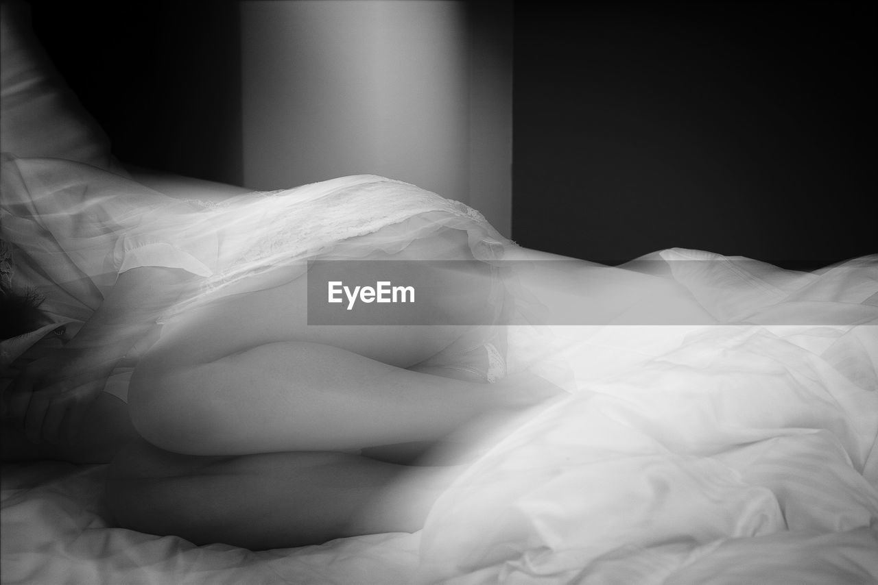Midsection of woman lying in bed