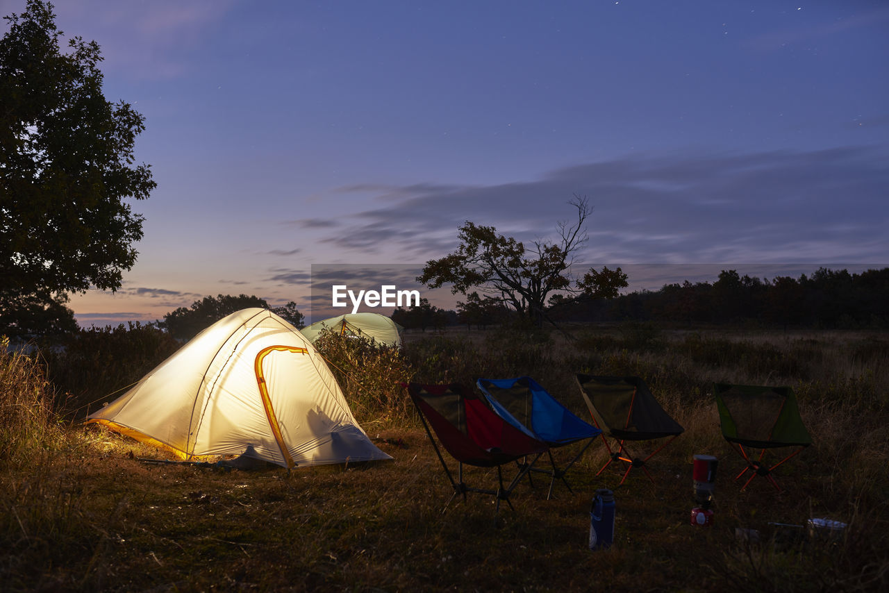 Lit up backpacking tents in field just before sunrise.