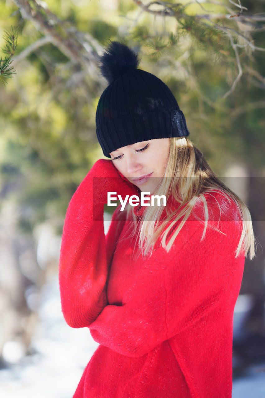 portrait of young woman standing against tree